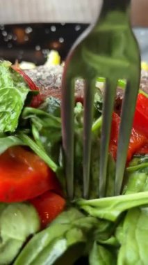 Güneş ışığında taze ıspanak yaprakları, havuç, salatalık ve vişneli domates salatasıyla servis edilen sulu ızgara domuz bifteği. Yüksek kalite 4k görüntü