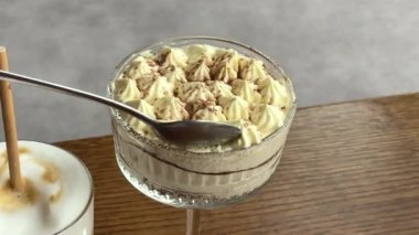 İtalyan kafe barında kaşıkla karıştırılmış bir fincan cappuccino tiramisu. İnsanlar şafakta İtalyan kahvaltısı yapıyor. İtalyan yaşam tarzı. Yavaş bir hareket yap. Yüksek kalite 4k görüntü