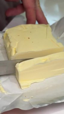 Mutfak bıçağını kapat. Kırsal ürünlerin arka planında tereyağı kes. Doğal çiftlik yiyeceği. Dikey çekim. Yüksek kalite 4k görüntü