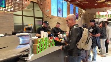 Roma 'daki Starbucks' tan müşterilerin kahve baristalarını severken, içki ve rafları markalı fincanlar ve satılık mallarla hazırlarken çekilmiş videolar. Roma, İtalya 12.16.2025
