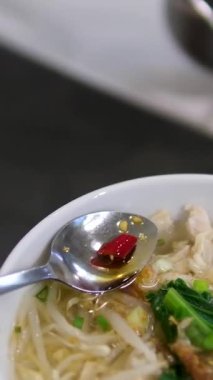 Erişteli sıcak domates çorbası içen bir kadın. Top balık sosu, acı biber sosu..