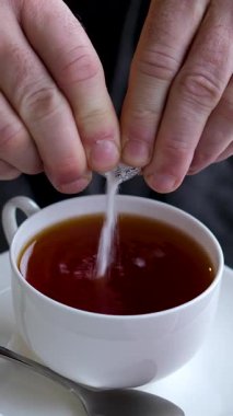 Çaya şeker dökmek, erkeklerin elleri tabakta, meyveler, elmalar, mandalinalar dizüstü bilgisayarın yanında. Yüksek kalite 4k görüntü