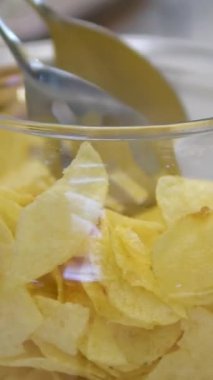Cam kâse. Yakın plan patates cipsi. Şeffaf kaseye düşen patates cipsi. Fast Food, Junk Food at Home. Çocukluk obezitesi. Yüksek kalorili yemek. Yüksek kalite 4k görüntü