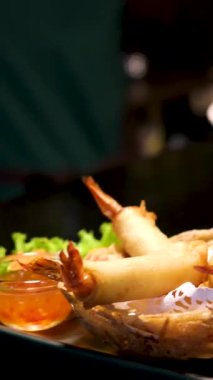 Close-up of grilled whole shrimp covered in green herb sauce, garnished with fresh cilantro leaves. High quality 4k footage