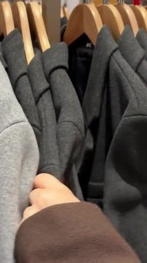 Gri kıyafetlerden renkli kıyafetlere kadar mağazada asılı duran kıyafetlerin yavaş çekim görüntüsü. Yüksek kalite 4k görüntü
