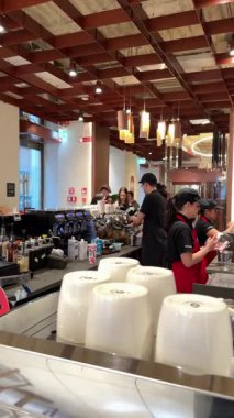 Roma 'daki Starbucks' tan müşterilerin kahve baristalarını severken, içki ve rafları markalı fincanlar ve satılık mallarla hazırlarken çekilmiş videolar. Roma, İtalya 12.16.2025