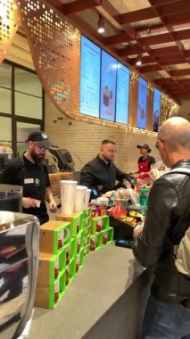 Roma 'daki Starbucks' tan müşterilerin kahve baristalarını severken, içki ve rafları markalı fincanlar ve satılık mallarla hazırlarken çekilmiş videolar. Roma, İtalya 12.16.2025