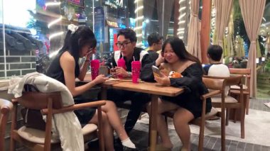 KATINAT Nguyen Van Thoai Vietnam 'da bir kafede canlı pembe bardaklar tutarken sosyal medyada iletişim ve telefon bağımlılığı eksikliği görülüyor. Vietnam Danang 12.18.2025