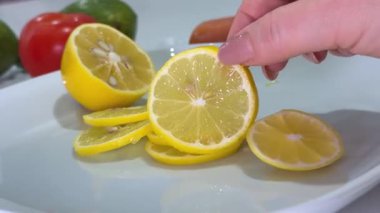 Tazelik. Göbekli bir kadın ev hanımlarının mutfağında taze limon keser. Ev hanımı ellerinin limon kesmesi çatal bıçak takımını ve malzemeyi kapsıyor. Yüksek kalite 4k