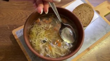 Sıcak sebze çorbası, kil kasede tavuk eti ve köy masasında servis ediliyor. Ön manzara, dikey olarak yaklaşırken. Küçük makarna.