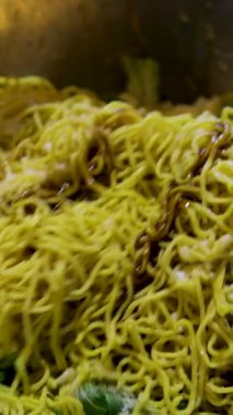 Bir tabak dolusu sebzeli kızarmış sarı şehriye. Tavada büyük kaşıklarla karıştırın.