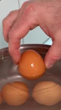 Bir adam tavuk yumurtalarını ocağın üstündeki bir tencerede su pişiren bir tencereye yerleştirir. Bu da ideal sert ya da yumuşak yumurta yapma tekniğini gösterir. Yüksek kalite 4k görüntü