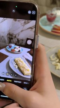 Bir kız yemeğinin fotoğrafını çeker: doldurulmuş lavaş, süzme peynirli krep ve bir restoranda süzme peynirli krep. Kızlar için iki porsiyon kahvaltı. Yüksek kalite 4k görüntü