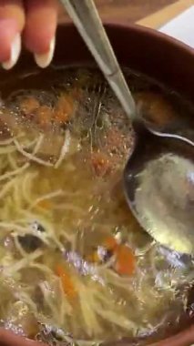 Sıcak sebze çorbası, kil kasede tavuk eti ve köy masasında servis ediliyor. Ön manzara, dikey olarak yaklaşırken. Küçük makarna.