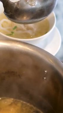 sıcak tencere pişirme fa pho çorba vietnam yakın çekim kızartma tavası et suyu pişirilmiş domuz kemikleri kız Vietnam 'da yemek pişirmek için bir restoran büfesinde yemeğini karıştırıyor.