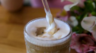 Buzlu bir kahveyi karamelli ve buzlu bir bardakla karıştırmak, yakından bakmak. Yüksek kalite 4k görüntü