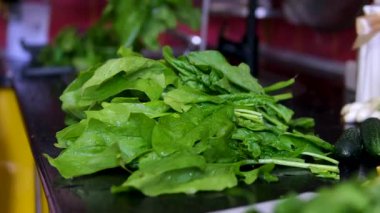 Ispanak yıkama ve haşlama süreci: erkeklerin ellerini suyun altında yıkamak, parçalara ayırmak, kızartma tavası atmak, karıştırmak, dondurmaya hazırlamak, ıspanaklı turta yapmak. Yüksek kalite 4k görüntü