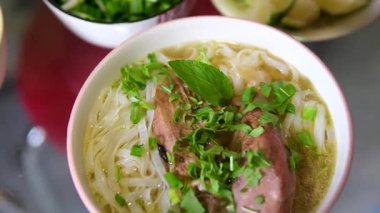 Geleneksel pho bo çorba hazırlama sıcak aromatik çorba pirinç vermicelli üzerine döküldü ardından taze otlar ve malzemeler lezzet dolu otantik bir sokak yemeği deneyimi yarattı.