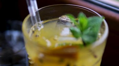 Buzlu bardağın yanında taze limonata, nane yaprakları ve limon dilimleri. Tutku meyvesi