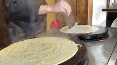 İnce krep sıcak tavada pişerken buhar yükselir ve kabarcıklar oluşur. Ev mutfağında gerçek zamanlı krep kızartma işlemini gösterir. Yüksek kalite 4k görüntü