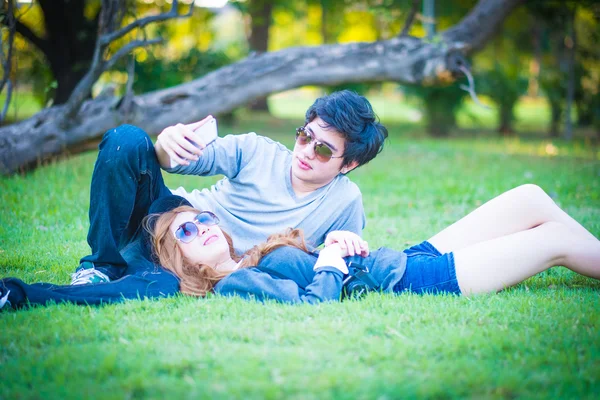 Couple couché sur l'herbe, parc, téléphone avec vue, entouré de nat — Photo