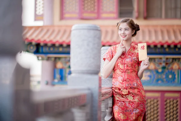 Азиатка в китайском платье держит двойку Лукратов — стоковое фото
