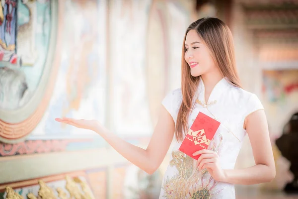Китаянка одевает традиционный чонгсам и держит красный конверт. — стоковое фото