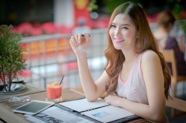 Güzel genç bayan yaz terasında oturup tablet ile 