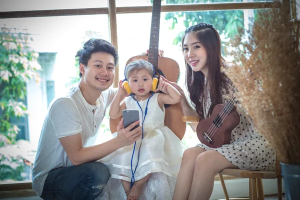 Familie mit kleinem Mädchen hört Musik auf dem Handy. — Stockfoto