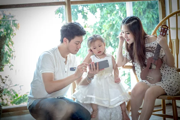 Familj med liten flicka i lyssna på musik på din telefon. — Stockfoto