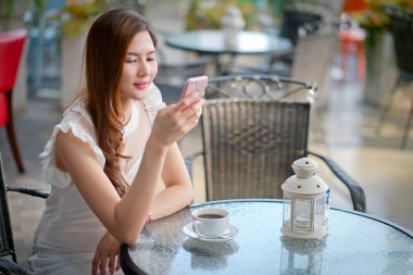 ile bir restoran terasında akıllı telefonda mesajlaşma Kız