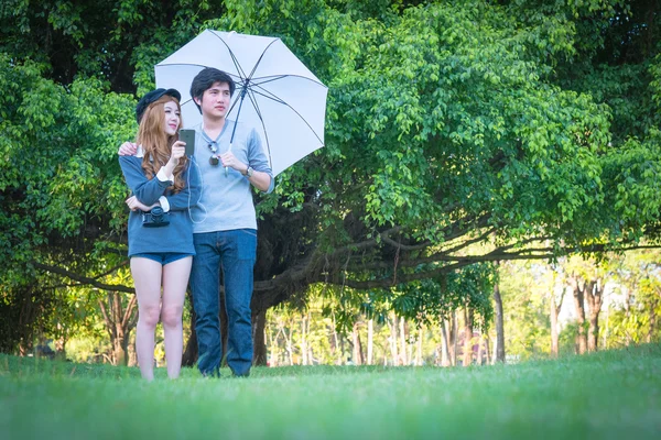 Casal de pé guarda-chuva branco Página verdejante árvores — Fotografia de Stock