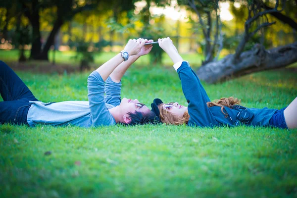 Couple couché sur l'herbe, parc, téléphone avec vue, entouré de nat — Photo