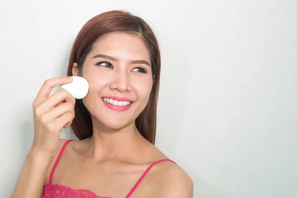 Beautiful young woman applying foundation to face with green egg — Stock Photo, Image