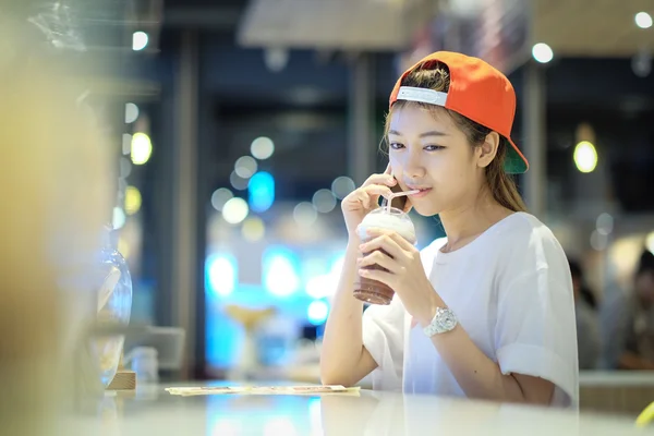 Молодая женщина пьет кофе со льдом в ресторане — стоковое фото