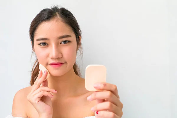 Young woman applying foundation on face with powder puff, — Stock Photo, Image