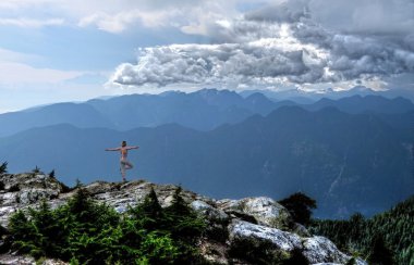 Storm is coming. Woman in yoga pose meditating in mountains.  clipart