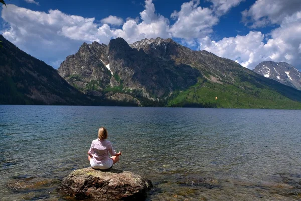 Mujer en yoga posan meditando junto al lago y las montañas . — Foto de Stock