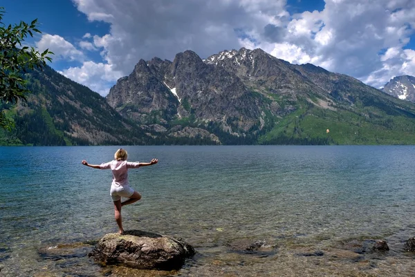 Mujer joven en pose de yoga junto al lago y las montañas . — Foto de Stock