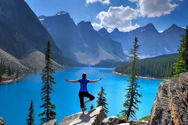 Woman in yoga pose at alpine lake and mountains. — Stock Photo, Image
