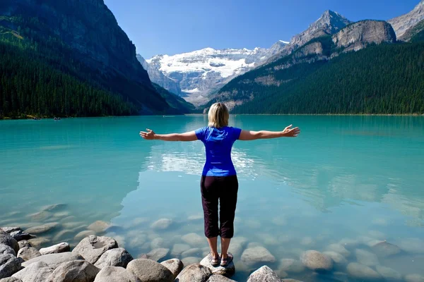 Mujer en yoga posando meditando por el agua . — Foto de Stock