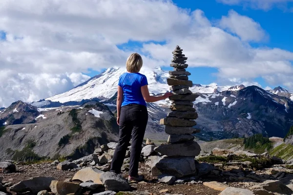 Vrouw op de bergtop met een stenen cairn. — Stockfoto