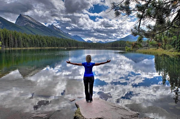 Mujer junto al lago alpino con montañas y nubes de reflexión . — Foto de Stock