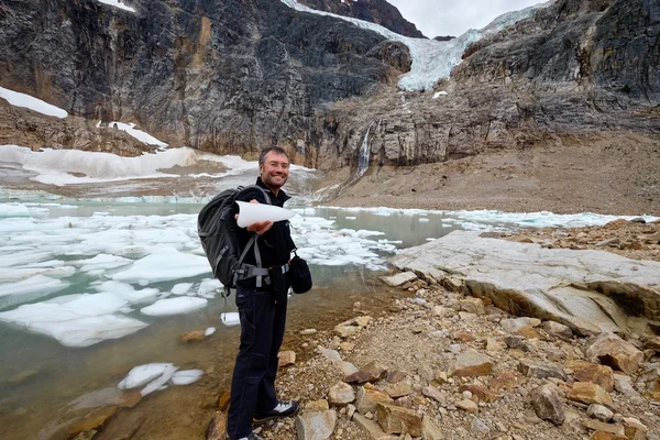 Man holding ice by lake with icebergs. — Stock Photo, Image