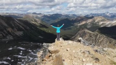 Dağın tepesinde elleri havada bir kadın yürüyüşçü. Daire çizerek uçan dronun görüntüsü. Pemberton ve Lytton. Stain Valley İl Parkı. İngiliz Kolombiyası. Kanada 