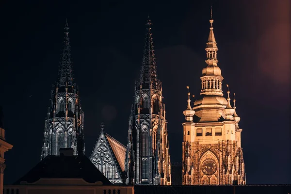 Çek Cumhuriyeti Prag Şatosu 'ndaki St. Vitus Katedrali' nin gece manzarası karanlık gece gökyüzüne karşı sıcak altın ve serin beyaz ışıklarla güzelce aydınlatılmış..