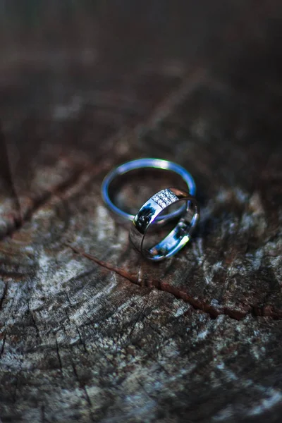 Ahşap bir yüzeye yerleştirilmiş elmaslarla, zarif gümüş alyansların yakın çekimi sonsuz aşkı, birliği ve bağlılığı simgeliyor..