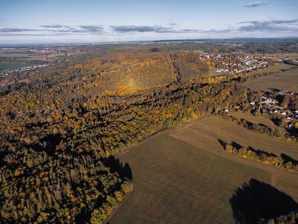Çek Cumhuriyeti 'ndeki renkli ağaçlar, kırsal arazi ve açık mavi gökyüzü altındaki küçük köy, sonbahar ormanlarının ve kırsal alanların havadan görünüşü.