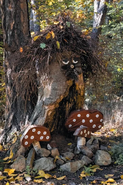 Ağaç gövdesi, çam kozalağı ve dallardan yapılmış orman ruhuna benzeyen ahşap süslemeler, sonbahar ormanlarında el yapımı ahşap mantarlarla çevrelenmiş..