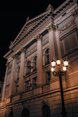 Prag Stavovsk divadlo 'nun muhteşem gece manzarası, sıcak sokak lambalarıyla aydınlatılıyor ve tarihi şehir merkezinde zarif klasik sütunları, süslemeleri ve rafine edilmiş mimari simetrisiyle sergileniyor..